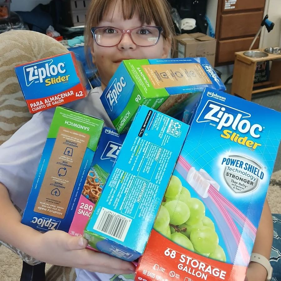 A volunteer holding boxes of donated Ziploc bags